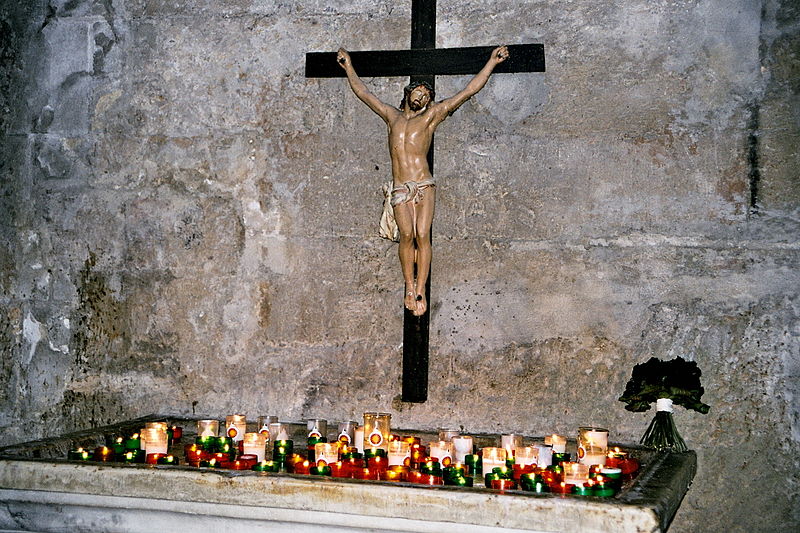 Votivkerzen vor einem Kruzifix, St-Vincent des Baux, Frankreich